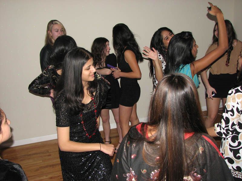 Group of young people dancing in a room. Some are smiling, and one person is pointing up.