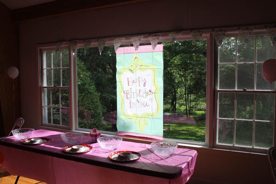 Pink-covered table with bowls, plates, and sign 
