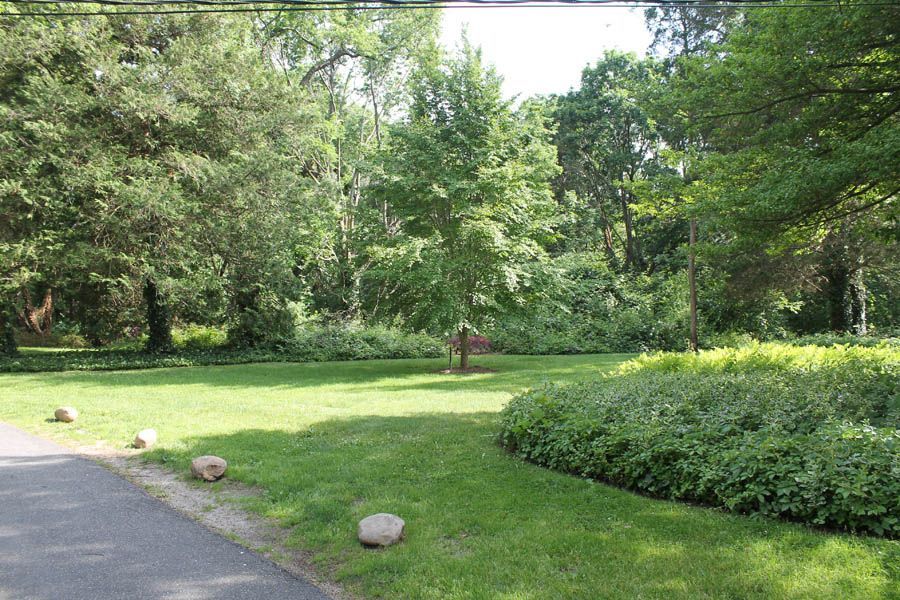 Green lawn with trees, shrubs, and a paved pathway. Overcast sky.