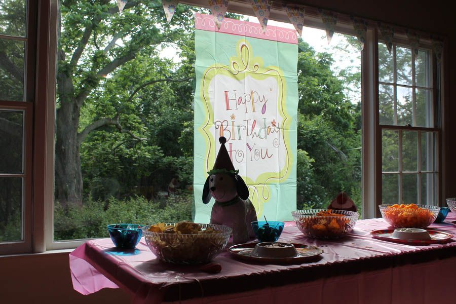 Birthday table set with a dog wearing a party hat, banner reads 