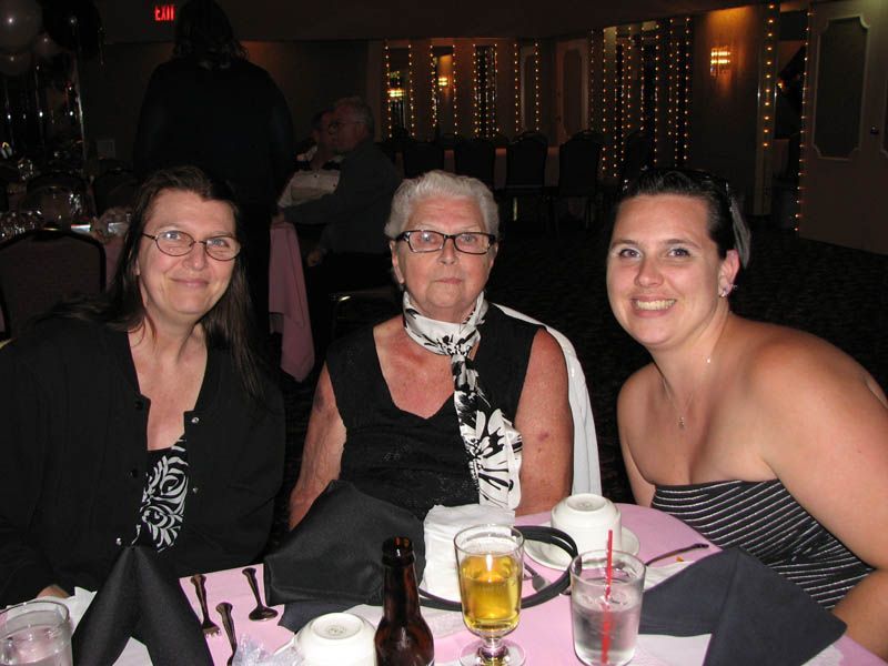 Three people seated at a table in a dimly lit room, possibly a restaurant. They smile at the camera.