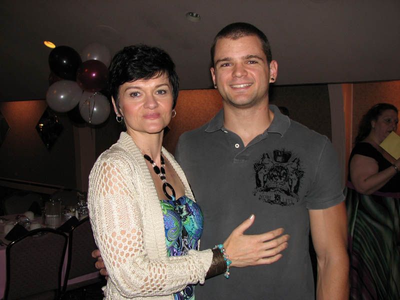 Woman in floral dress and man in polo shirt pose for a photo at an event.