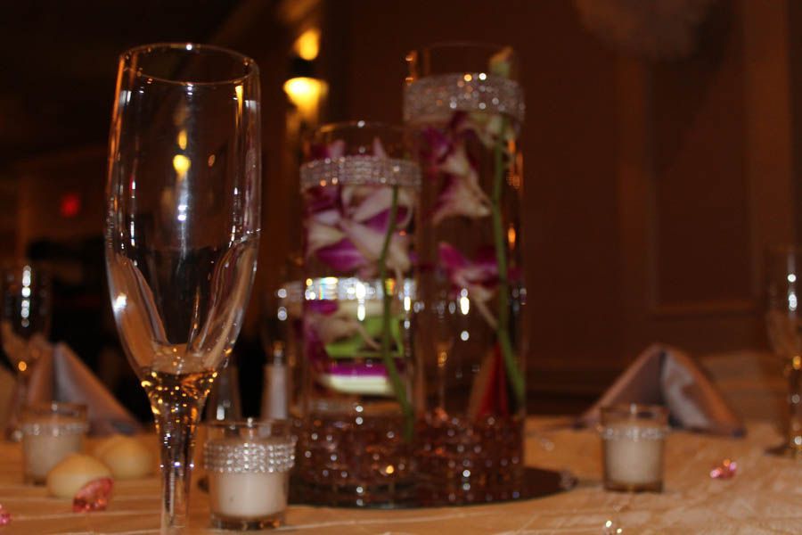 Champagne glass in focus; blurred table setting with flower centerpieces and candles.