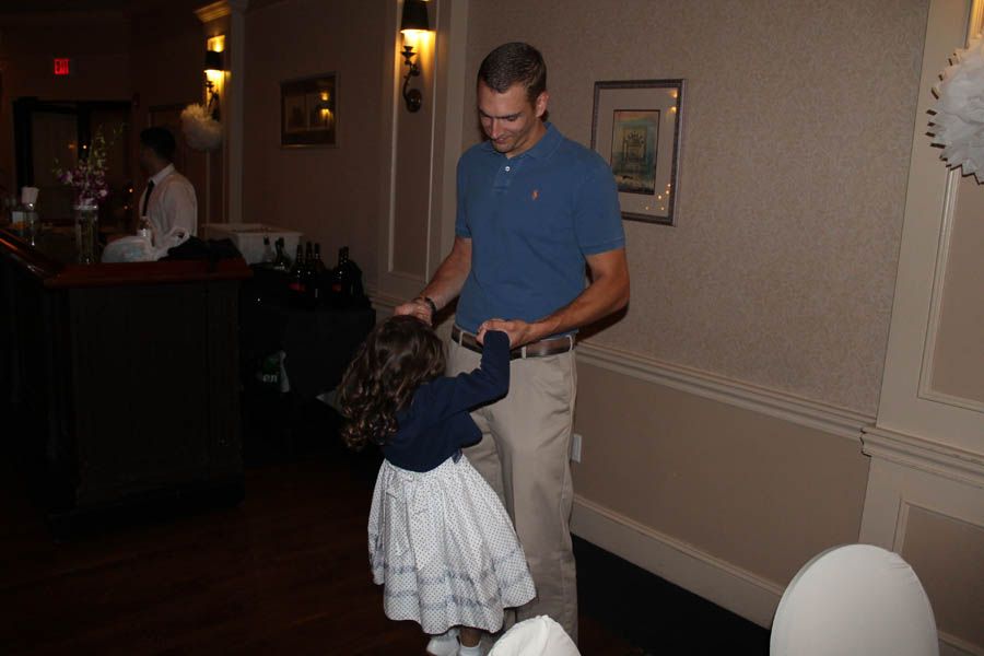 Man twirling a young child in a room with a bar, tan walls, and a small picture on the wall.