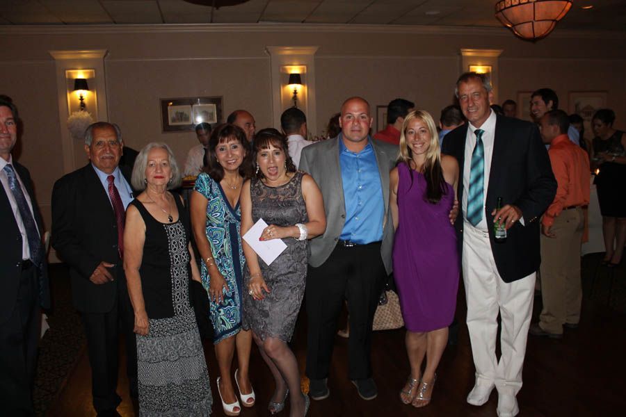 Group of people in formal attire, smiling at a gathering indoors.