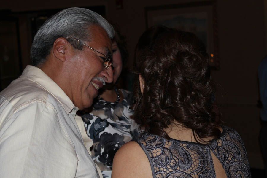 Man in light shirt laughs while talking to a woman with dark curly hair at an event.