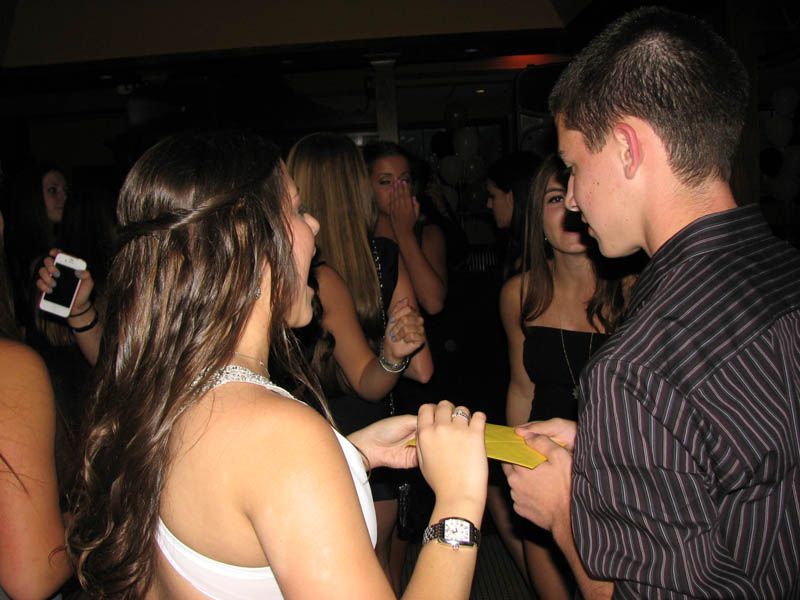 People in a dark club, one giving a yellow card to another. Other people are in the background.