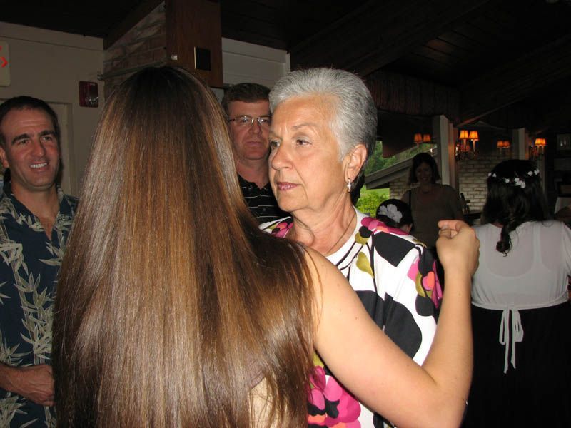 Woman dancing with another person, floral shirt, others watching.