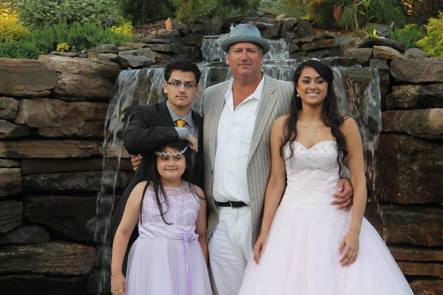 Family posing in front of a waterfall. Two adults and two children in formal wear.