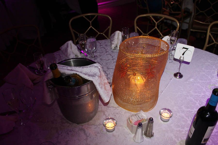 Table setting with ice bucket, gold lantern, wine bottle, and number 7.