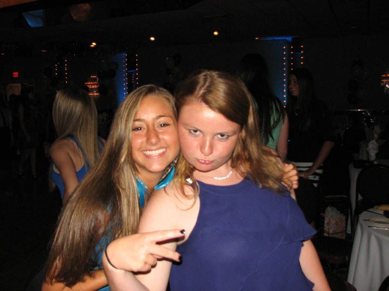 Two young women posing at a formal event, one smiling, the other making a face.