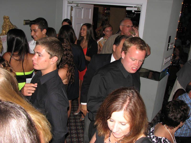 People gathered in a room, some looking at camera, others towards an open doorway.