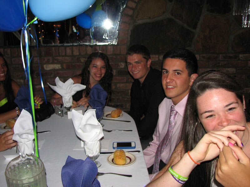 Group of friends smiling at a restaurant table with blue balloons and decorations.
