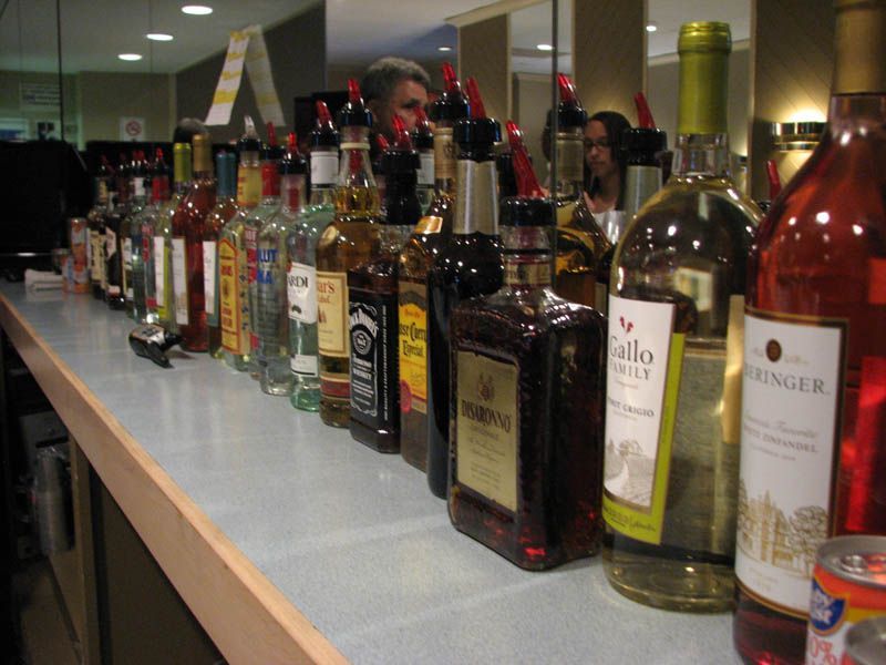 Bar with numerous liquor bottles lined up, some with pour spouts.