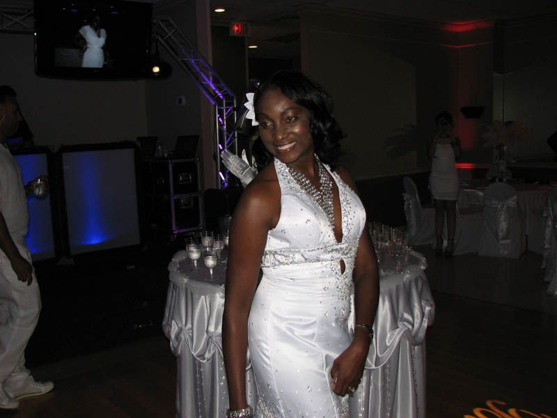 Woman in white gown smiles at camera in a banquet hall.