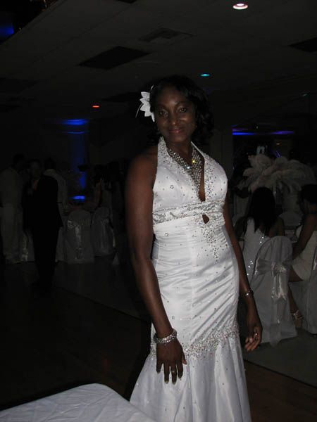 Woman in white halter wedding dress, standing indoors.