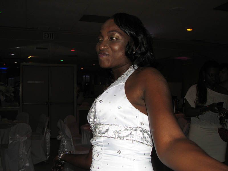 Woman in a white dress, smiling. Indoors, possibly a dance floor setting.