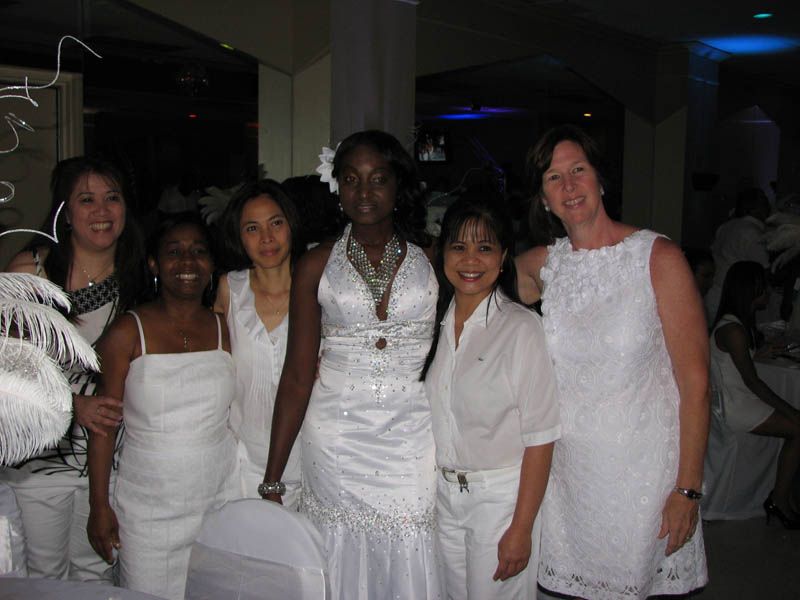 Group of six people in white outfits at an event.