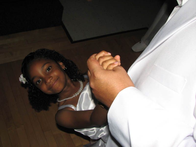 Girl in white dress holding hands, looking up smiling at someone.