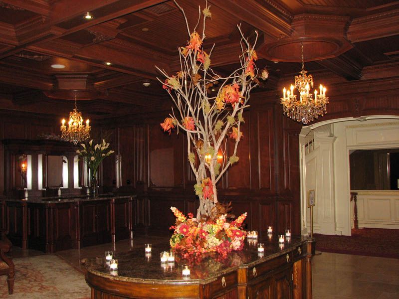 Elegant bar area with a large floral arrangement and chandeliers. Wooden paneling.