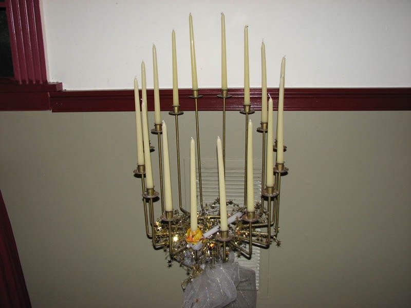 Large brass chandelier with lit candles hanging from a high ceiling.