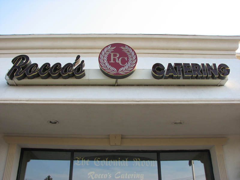 Rocco's Catering sign above a store entrance, with the business name and logo displayed.