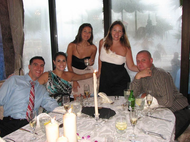 Group of people around a table, celebrating. A woman holds a candle. Champagne glasses on the table.