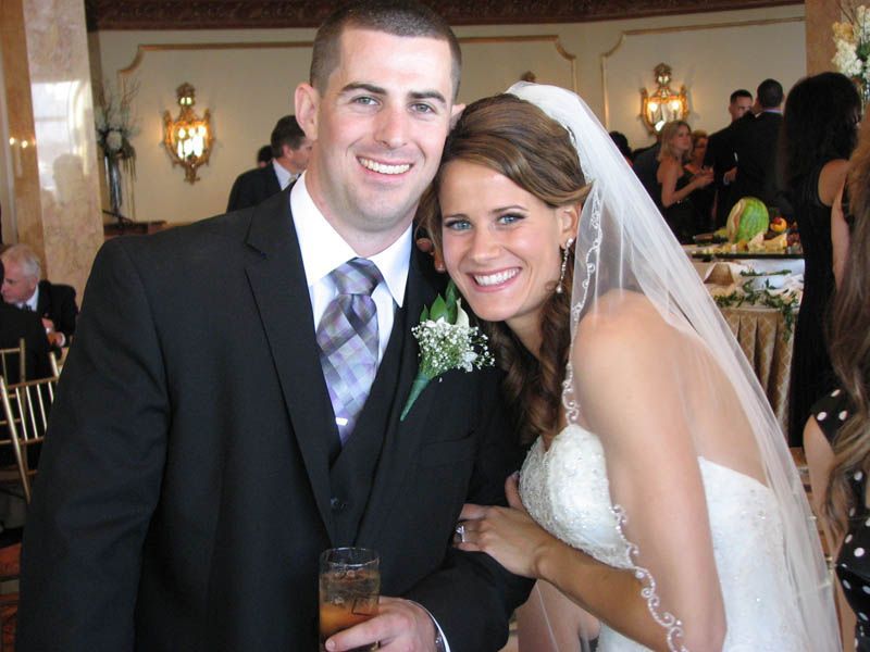 Bride and groom smiling at a wedding, formal attire, ornate setting.