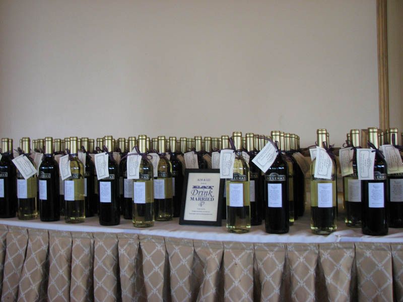 Bottles of wine on a table with white tags. A sign reads 