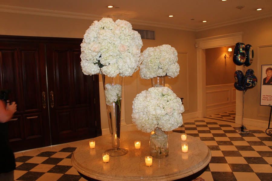 Floral centerpieces on a round table, lit candles, celebration decorations, party.