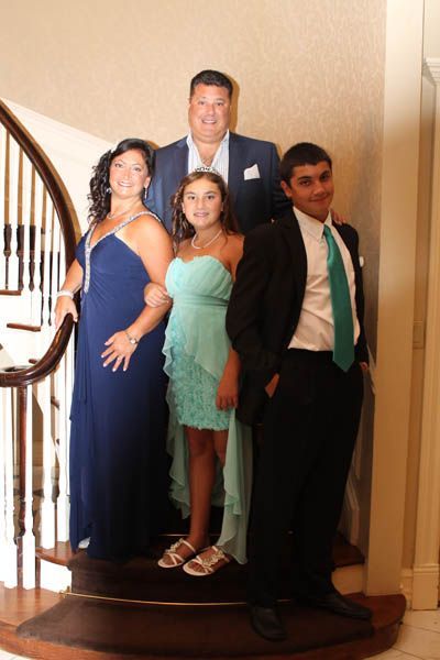 Family dressed in formal attire on a staircase, posing for a photo.