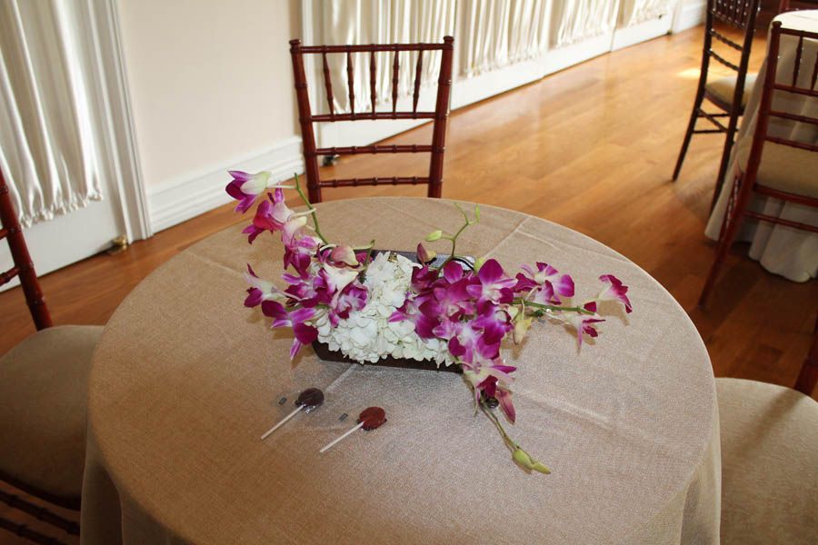 Round table with floral centerpiece and lollipops, set in a room with wood flooring and chairs.