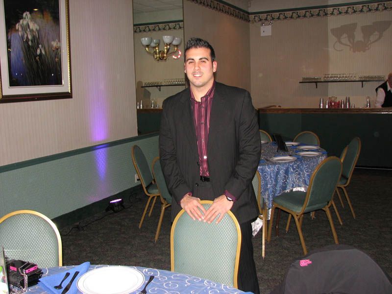 Man in suit stands by a table set for a formal event.