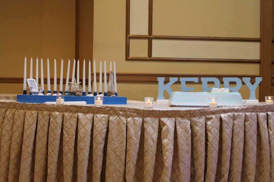 Table set for a party, with a cake, candles, and blue letters that spell 