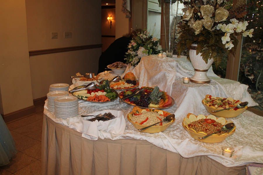 Buffet table with various food dishes, white linens, and floral arrangements.