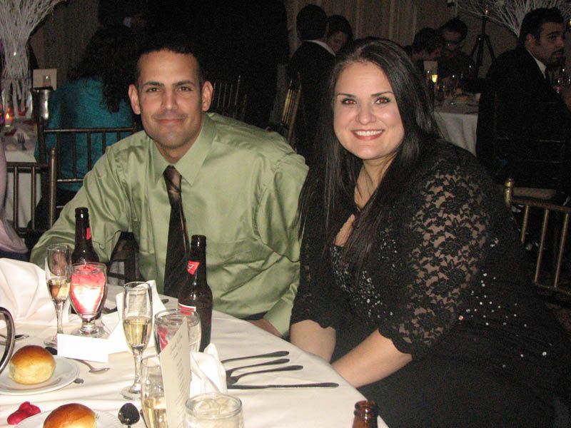 A man and woman smiling at a table set for a formal event.