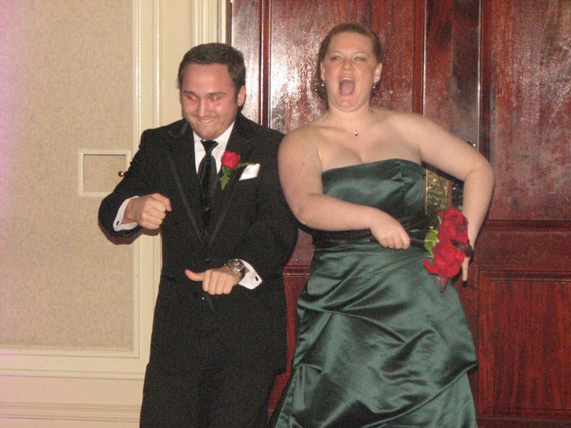Couple in formal wear dancing and smiling. The woman in a green dress and the man in a tuxedo.