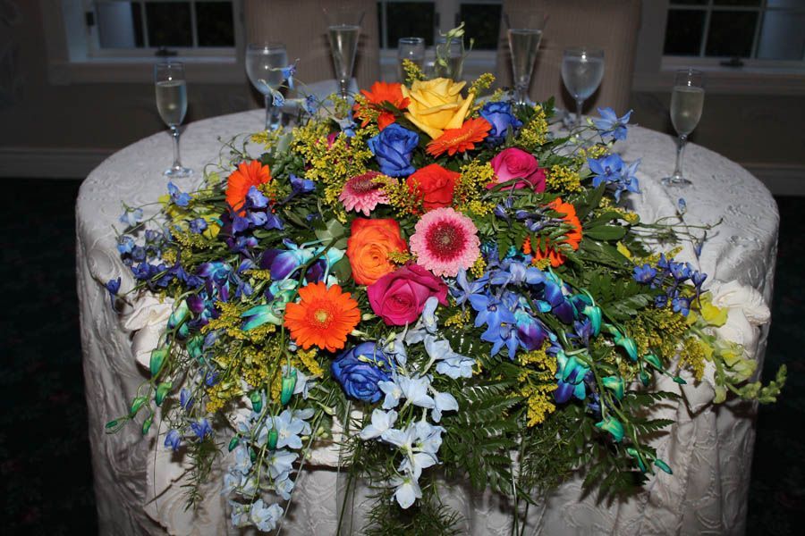 A round table with a bright floral centerpiece and champagne flutes.