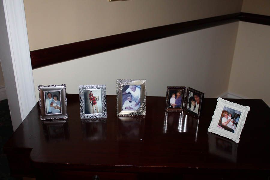 Six framed photos displayed on a dark wooden surface in front of a staircase.