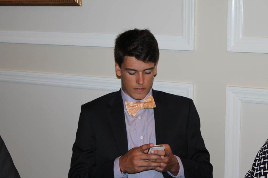 Man in a suit and bow tie looking at a phone.
