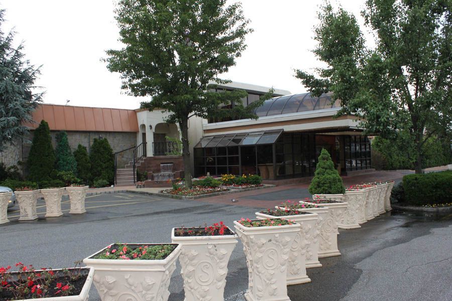 A building with a glass enclosed entrance and outdoor planters filled with flowers.