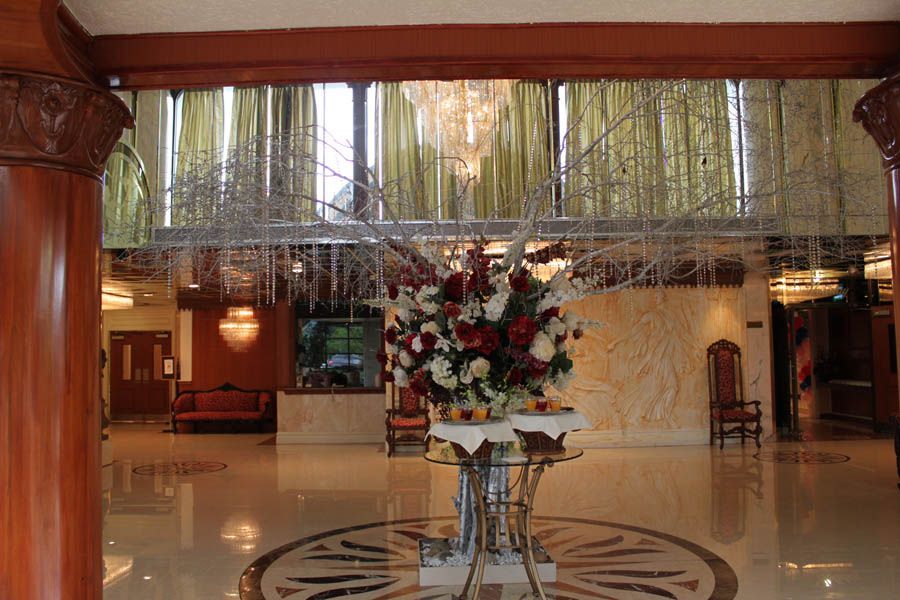 Hotel lobby with floral arrangement, chandelier, and columns. Marble floor, ornate decor.