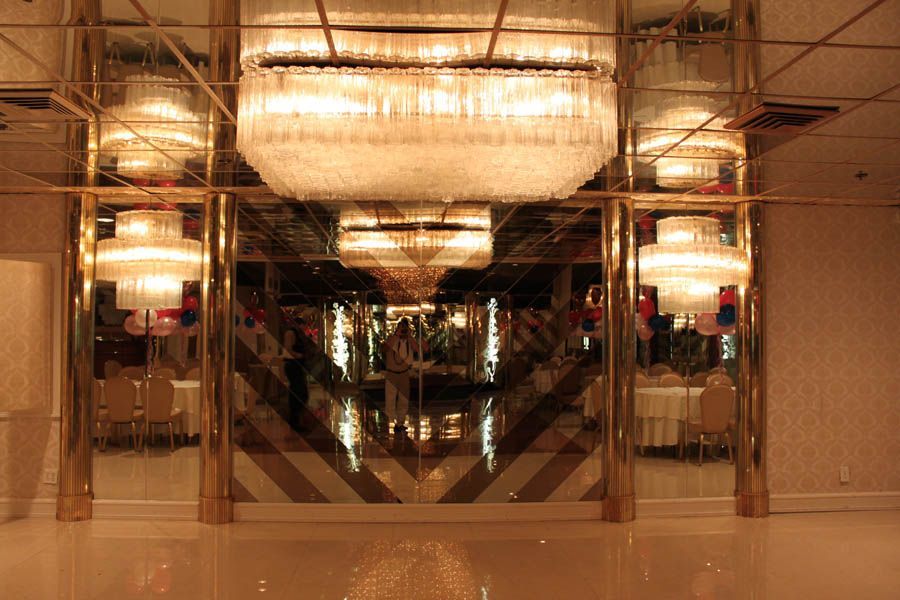Grand ballroom with mirrored walls, chandeliers, and golden accents.