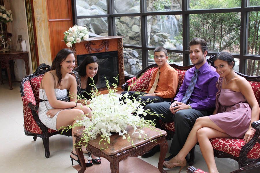 Five people sit on a red patterned couch with a small table in front. They are in a room with a large window and fireplace.