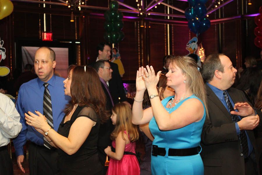 People clapping and dancing at a party in a decorated room with balloons.