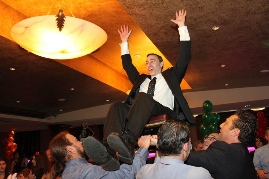 Man being held up in the air by a group, celebrating at a party.