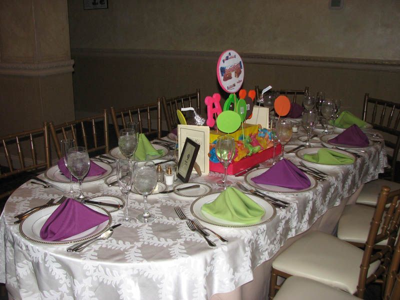Formal dining table set with place settings and colorful napkins, party centerpiece, and decorations.