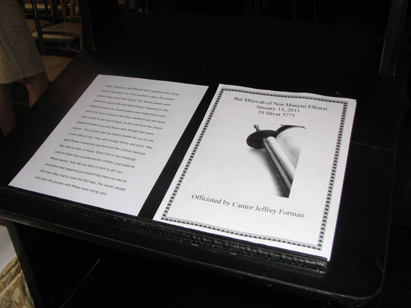 Two white printed pages on a black surface. One has text, the other has a title: 