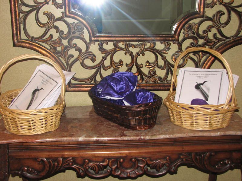 Three wicker baskets on a table: two with papers, one with purple fabric, in front of a decorative mirror.