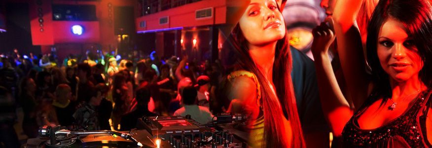 People dancing in a crowded, dimly lit nightclub, illuminated by red and purple lights.